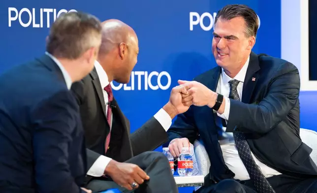 Maryland Gov. Wes Moore, center, fist bumps Oklahoma Gov. Kevin Stitt at an event at the National Governors Association Winter Meeting, Thursday, Feb. 19, 2026, in Washington. (AP Photo/Allison Robbert)