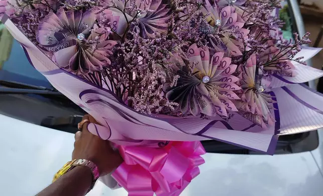 A vendor holds a flower bouquet that incorporates real money in Nairobi, Kenya, Nov. 25, 2025. (AP Photo/Duke Monari)