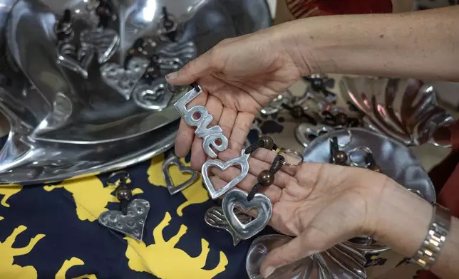 Stephanie Charlton, the owner of a gift shop that retails in recycled aluminium gifts, holds "love" signs in Harare, Zimbabwe, Wednesday, Feb. 11, 2026. (AP Photo/Aaron Ufumeli)