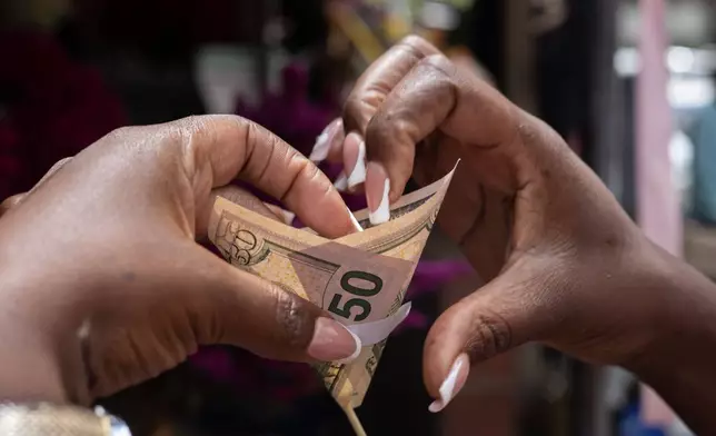 A florist makes a money bouquet designed for Valentine's Day at his stall in Harare, Zimbabwe, Tuesday, Feb. 10, 2026. (AP Photo/Aaron Ufumeli)
