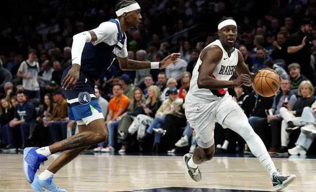 Portland Trail Blazers guard Jrue Holiday, right, works around Minnesota Timberwolves forward Jaden McDaniels during the first half of an NBA basketball game, Wednesday, Feb. 11, 2026, in Minneapolis. (AP Photo/Matt Krohn)