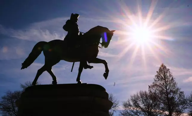 The sun shines over a statue of George Washington on horseback at the Public Garden, Friday, Feb. 13, 2026, in Boston. (AP Photo/Charles Krupa)