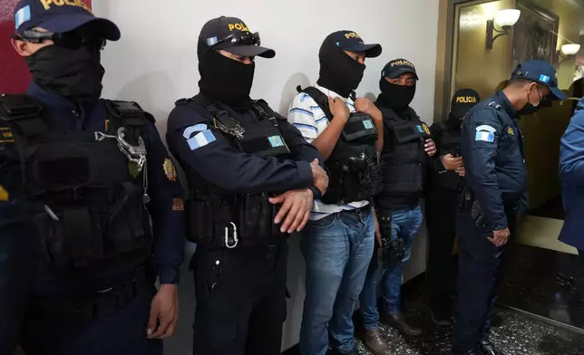 Police officers stand by as Attorney General agents conduct a raid at Club La Aurora where Bar Association members were meeting to vote for representatives to serve on the Constitutional Court, in Guatemala City, Thursday, Feb. 12, 2026.(AP Photo/Moises Castillo)