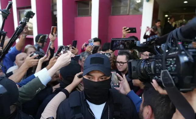 A security guard stands amid reporters as agents from the Attorney General's office conduct a raid at Club La Aurora where Bar Association members were meeting to vote for representatives to serve on the Constitutional Court, in Guatemala City, Thursday, Feb. 12, 2026. (AP Photo/Moises Castillo)