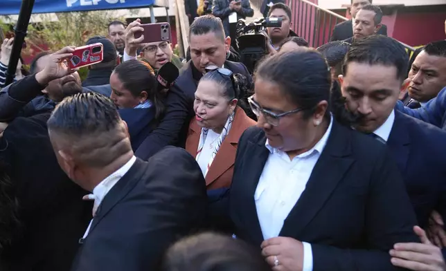 Guatemalan General Attorney Consuelo Porras, center, is escorted by her security team after voting in an election for the magistrates who will represent the bar association on the Constitutional Court in Guatemala City, Thursday, Feb. 12, 2026. (AP Photo/Moises Castillo)