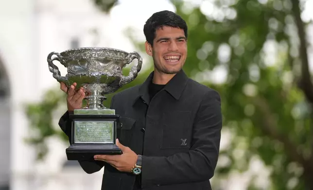 Carlos Alcaraz of Spain smiles as he poses with the Norman Brookes Challenge Cup the morning after defeating Novak Djokovic of Serbia in the men's singles final at the Australian Open tennis championship, in Melbourne, Australia, Monday, Feb. 2, 2026. (AP Photo/Dita Alangkara)