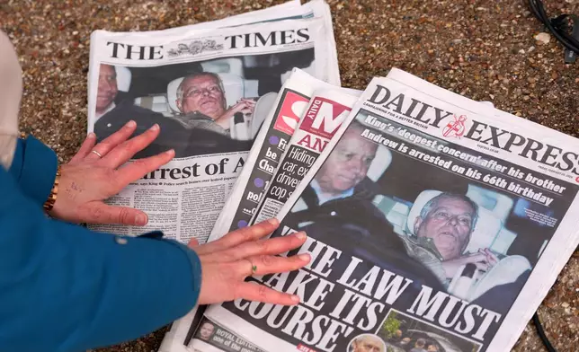 A journalist looks at today's newspaper front pages in London, Friday, Feb. 20, 2026 after Andrew Mountbatten-Windsor was arrested and held for hours by British police on suspicion of misconduct in public office related to his links to Jeffrey Epstein.(AP Photo/Kin Cheung)
