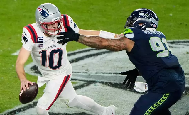 New England Patriots quarterback Drake Maye (10) escapes pressure from Seattle Seahawks defensive tackle Byron Murphy II (91) during the second half of the NFL Super Bowl 60 football game, Sunday, Feb. 8, 2026, in Santa Clara, Calif. (AP Photo/Charlie Riedel)