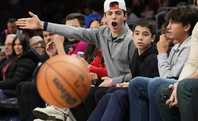 Lucas Gonzalez, 16, center, reacts to a play as he sits courtside with Matias Gonzalez, 13, second from right, and Sergio Masvidal, 15, right, during the first half of an NBA basketball game, Sunday, Feb. 1, 2026, in Miami. (AP Photo/Lynne Sladky)