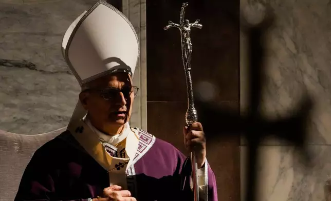 The shadow of the crucifix surmounting his pastoral staff falls across Pope Leo XIV as he presides over Ash Wednesday Mass, marking the start of Catholic Lent, inside the Basilica of Santa Sabina in Rome, Wednesday, Feb. 18, 2026. (AP Photo/Gregorio Borgia)