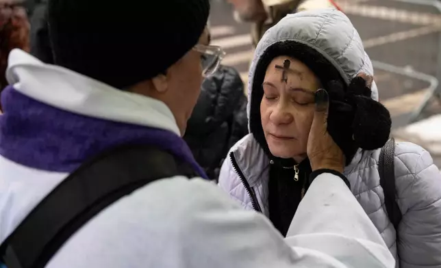 Father Fabian Arias places an ash cross on the forehead of a devotee during Ash Wednesday outside the Jacob K. Javits federal building, Wednesday, Feb. 18, 2026, in New York. (AP Photo/Yuki Iwamura)