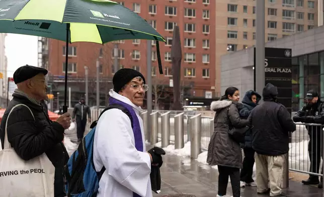 Father Fabian Arias waits for a devotee to place an ash cross on the forehead during Ash Wednesday outside the Jacob K. Javits federal building, Wednesday, Feb. 18, 2026, in New York. (AP Photo/Yuki Iwamura)