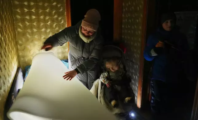 Yuliia Dolotova, 37, uses foam rubber to insulate her children’s bed in her apartment during a power outage caused by Russia’s repeated air strikes on the country’s power grid, in Kyiv, Ukraine, Monday, Feb. 2, 2026. (AP Photo/Sergey Grits)