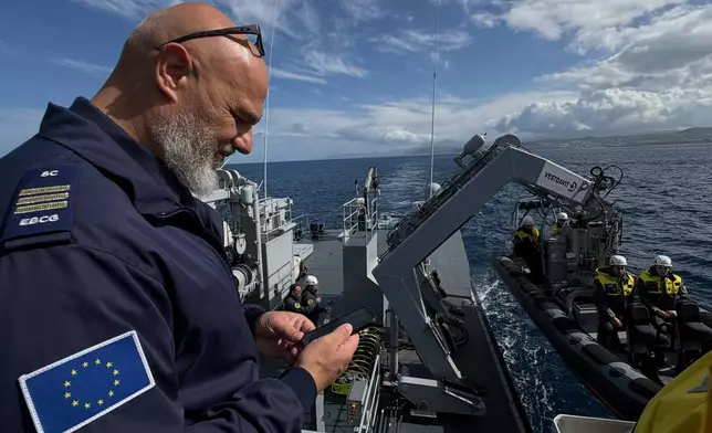 Frontex Contingent Commander Georgios Pyliaros takes pictures of Frontex officers from the Guardia di Finanza OPV Osum as they prepare in their speedboat to be lowered into the sea during a patrol in the Aegean Sea near Heraklion, Crete, Greece, Monday, Feb. 16, 2026. (AP Photo/Lefteris Pitarakis)