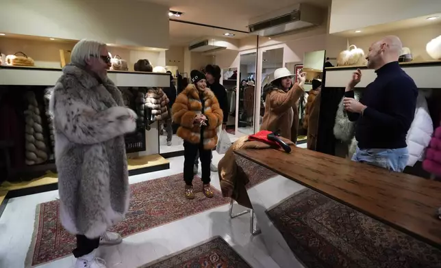 From left, Stefano Vannicola, Silvia Antelli, and Stefania Damiani browse the local branch of Pajaro, a luxury Italian fashion brand, while chatting with sales manager Marco Molinari in Cortina d'Ampezzo, Italy, Saturday, Feb. 14, 2026. (AP Photo/Alessandra Tarantino)