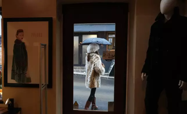 A woman wearing a lynx fur coat leaves Pajaro, a luxury Italian fashion brand in Cortina d'Ampezzo, Italy, Saturday, Feb. 14, 2026. (AP Photo/Alessandra Tarantino)