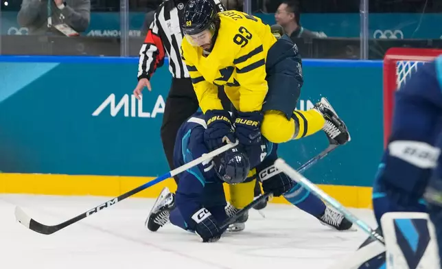 Sweden's Mika Zibanejad, up, challenges Finland's Miro Heiskanen during a preliminary round match of men's ice hockey between Finland and Sweden at the 2026 Winter Olympics, in Milan, Italy, Friday, Feb. 13, 2026. (AP Photo/Hassan Ammar)