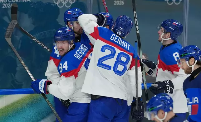 Slovakia's Adam Ruzicka, obscured behind, celebrates scoring a goal in the third period with teammates, Peter Ceresnak (14), Martin Gernat (28), Oliver Okuliar (8) and Pavol Regenda (84) during a preliminary round match of men's ice hockey between Italy and Slovakia at the 2026 Winter Olympics, in Milan, Italy, Friday, Feb. 13, 2026. (AP Photo/Carolyn Kaster)