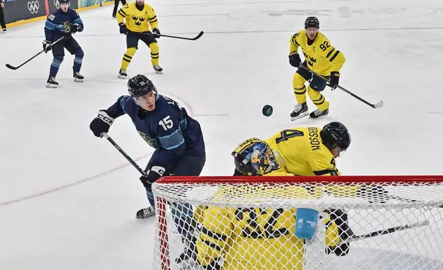 Finland's Anton Lundell, left, scores his team's second goal past Sweden's Filip Gustavsson, during a preliminary round match of men's ice hockey between Finland and Sweden at the 2026 Winter Olympics, in Milan, Italy, Friday, Feb. 13, 2026. (Alexander Nemenov/Pool Photo via AP)