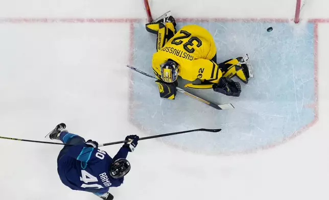 Finland's Joel Armia, left, scores his sides third goal past Sweden's goalkeeper Filip Gustavsson during a preliminary round match of men's ice hockey between Finland and Sweden at the 2026 Winter Olympics, in Milan, Italy, Friday, Feb. 13, 2026. (AP Photo/Petr David Josek)