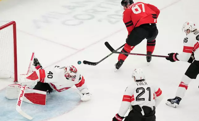 Canada's Sidney Crosby, right, fails to score past Switzerland's goalkeeper Akira Schmid during a preliminary round match of men's ice hockey between Canada and Switzerland at the 2026 Winter Olympics, in Milan, Italy, Friday, Feb. 13, 2026. (AP Photo/Hassan Ammar)