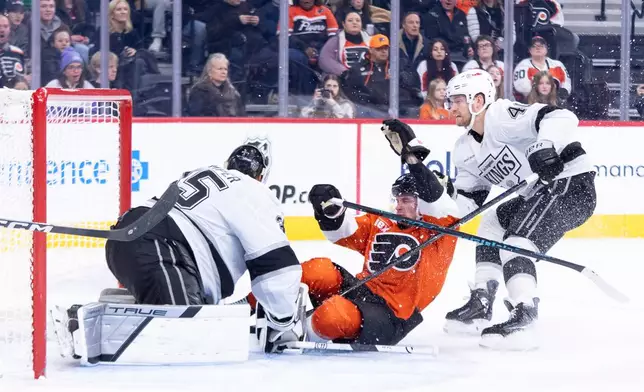 Philadelphia Flyers' Trevor Zegras, center, slides into Los Angeles Kings' Darcy Kuemper, left, as Joel Armia, right, is behind him during the second period of an NHL hockey game, Saturday, Jan. 31, 2026, in Philadelphia. (AP Photo/Chris Szagola)
