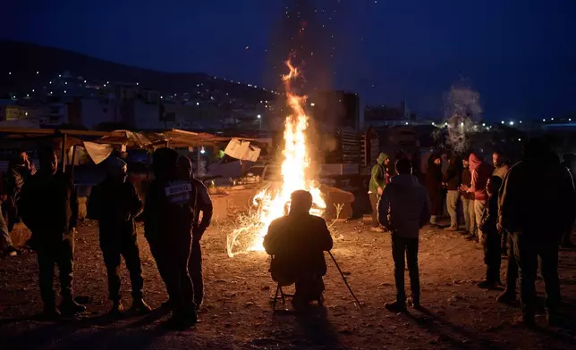 Palestinians warm themselves next to the bonfire as they gather at a livestock market near Balata refugee camp on the outskirts of the West Bank city of Nablus, Thursday, Feb. 12, 2026. (AP Photo/Leo Correa)