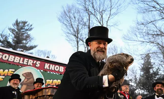 Groundhog Club handler A.J. Dereume holds Punxsutawney Phil, the weather prognosticating groundhog, during the 140th celebration of Groundhog Day on Gobbler's Knob in Punxsutawney, Pa., Monday, Feb. 2, 2026, Phil's handlers said that the groundhog has forecast six more weeks of winter. (AP Photo/Barry Reeger)