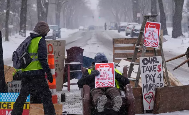 A person walks near a blockade set up to deter federal immigration enforcement vehicles In Minneapolis, Sunday, Feb. 1, 2026. (AP Photo/Alex Brandon)
