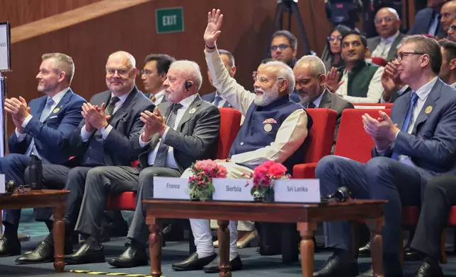 In this photo provided by Indian Prime Minister's Office, lndia's Prime Minister Narendra Modi, center, raises his hand in acknowledgment as other foreign dignitaries clap during the AI Summit in New Delhi, India, Thursday, Feb. 19, 2026. (Indian Prime Minister's Office via AP)