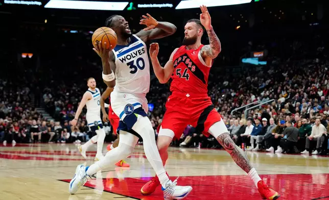 Minnesota Timberwolves' Julius Randle (30) drives at Toronto Raptors' Sandro Mamukelashvili (54) during the first half of an NBA basketball game in Toronto, Wednesday, Feb. 4, 2026. (Frank Gunn/The Canadian Press via AP)