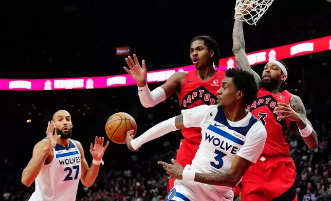 Minnesota Timberwolves' Jaden McDaniels (3) passes to Rudy Gobert (27) as Toronto Raptors' Collin Murray-Boyles (top left) and Brandon Ingram (right) defend during the first half of an NBA basketball game in Toronto, Wednesday, Feb. 4, 2026. (Frank Gunn/The Canadian Press via AP)
