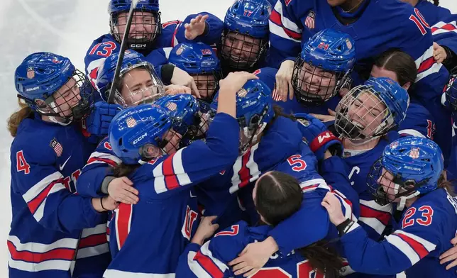 United States players surround Megan Keller (5) after she scored the winning goal in overtime to beat Canada in the women's ice hockey gold medal game at the 2026 Winter Olympics, in Milan, Italy, Thursday, Feb. 19, 2026. (AP Photo/Carolyn Kaster)