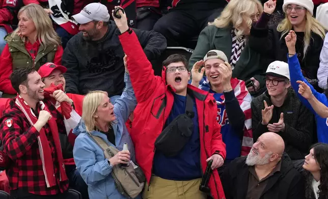 A fan celebrates after catching a puck during the second period of the women's ice hockey gold medal game between the United States and Canada at the 2026 Winter Olympics, in Milan, Italy, Thursday, Feb. 19, 2026. (AP Photo/Carolyn Kaster)