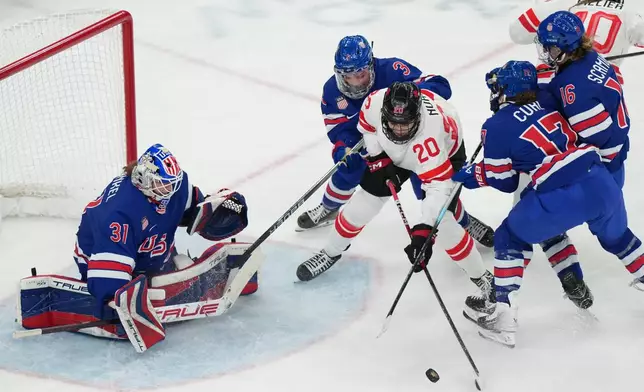 Canada's Sarah Nurse (20) is defended by United States' Cayla Barnes (3) and Britta Curl (17) as she tries to control the puck in front of goalkeeper Aerin Frankel (31) during the second period of the women's ice hockey gold medal game at the 2026 Winter Olympics, in Milan, Italy, Thursday, Feb. 19, 2026. (AP Photo/Carolyn Kaster)
