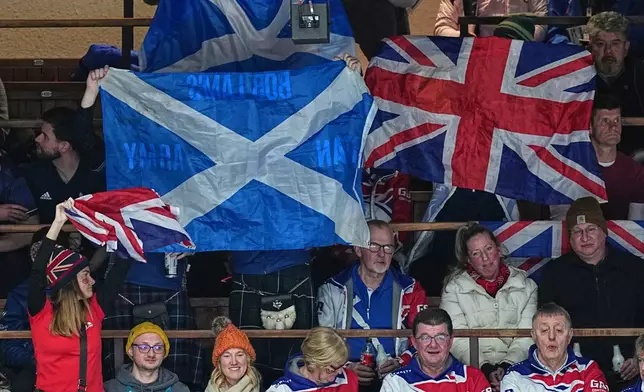 Britain's fans wave flags during a men's curling gold medal match between Britain and Canada, at the 2026 Winter Olympics, in Cortina d'Ampezzo, Italy, Saturday, Feb. 21, 2026. (AP Photo/Fatima Shbair)