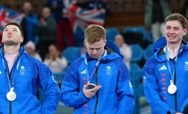 From left, Britain's Hammy McMillan, Bobby Lammie and Grant Hardie pose with the silver medals of the men's curling, at the 2026 Winter Olympics, in Cortina d'Ampezzo, Italy, Saturday, Feb. 21, 2026. (AP Photo/Misper Apawu)