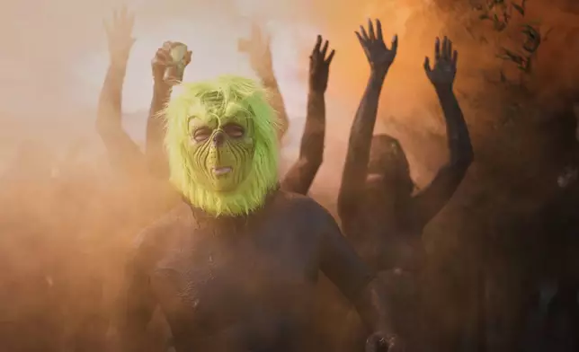 A reveler donning a Grinch mask strikes a pose during the Mud Block carnival party in Paraty, Brazil, Saturday, Feb. 14, 2026. (AP Photo/Andre Penner)