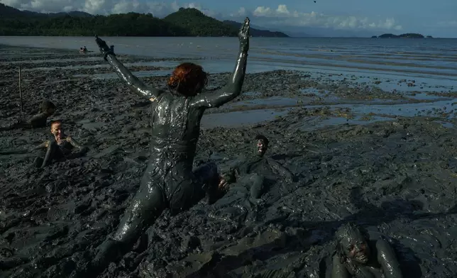 A reveler jumps into a puddle of mud during the Mud Block carnival party in Paraty, Brazil, Saturday, Feb. 14, 2026. (AP Photo/Andre Penner)