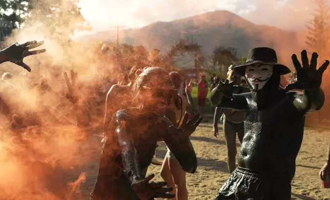 Revelers strikes poses during the Mud Block carnival party in Paraty, Brazil, Saturday, Feb. 14, 2026. (AP Photo/Andre Penner)