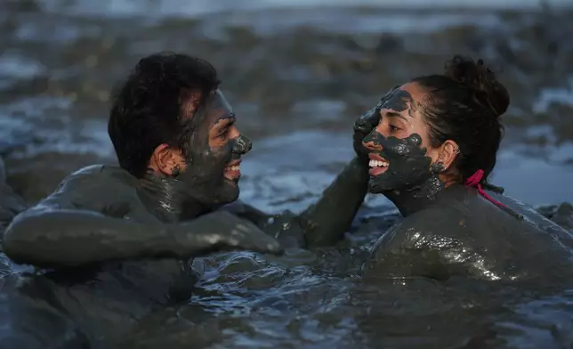 A man smears mud on a fellow reveler during the Mud Block carnival party in Paraty, Brazil, Saturday, Feb. 14, 2026. (AP Photo/Andre Penner)
