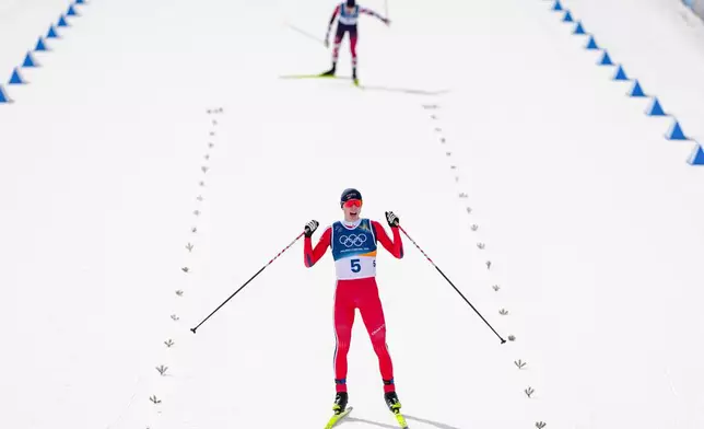 Jens Luraas Oftebro, of Norway, crosses the finish line, ahead of Johannes Lamparter, of Austria, to win the gold medal in the nordic combined individual Gundersen large hill/10km at the 2026 Winter Olympics, in Tesero, Italy, Tuesday, Feb. 17, 2026. (AP Photo/Kirsty Wigglesworth)