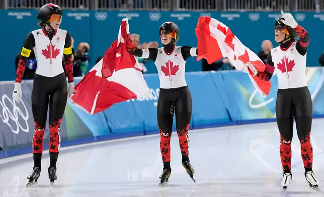 Team Canada with Ivanie Blondin, center and white armband, Valerie Maltais, right and red armband, and Isabelle Weidemann, left and yellow armband, celebrate winning the gold medal in the final of the women's team pursuit speedskating race at the 2026 Winter Olympics, in Milan, Italy, Tuesday, Feb. 17, 2026. (AP Photo/Ben Curtis)