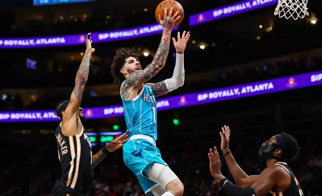 Charlotte Hornets guard LaMelo Ball, center, goes up to shoot against Atlanta Hawks guard Nickeil Alexander-Walker, left, and forward Onyeka Okongwu, right, during the first half of an NBA basketball game, Saturday, Feb. 7, 2026, in Atlanta. (AP Photo/Colin Hubbard)