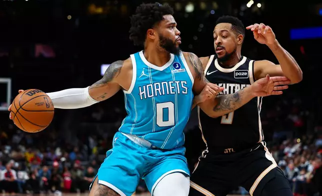 Charlotte Hornets forward Miles Bridges (0) dribbles against Atlanta Hawks guard CJ McCollum, right, during the first half of an NBA basketball game, Saturday, Feb. 7, 2026, in Atlanta. (AP Photo/Colin Hubbard)