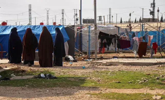 Unidentified women stand in a section of the camp housing Australian family members of suspected Islamic State militants who were returned to due to unspecified procedural issues following an attempted repatriation by Syrian authorities, in the Roj Camp in eastern Syria, Monday, Feb. 16, 2026. (AP Photo/Baderkhan Ahmad)