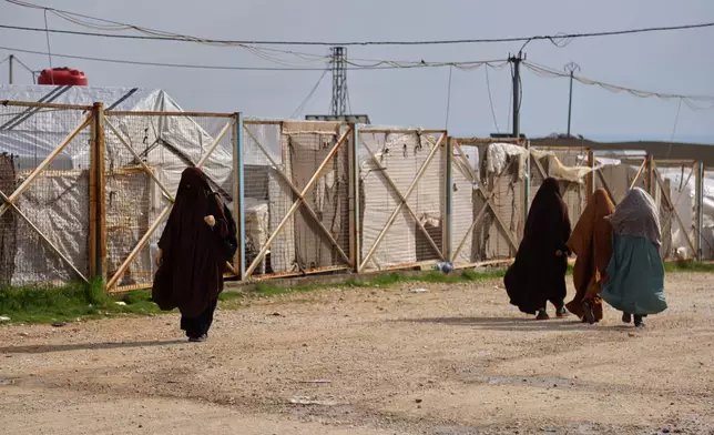 Unidentified women move through the camp holding family members of suspected Islamic State militants in the Roj Camp in eastern Syria, Monday, Feb. 16, 2026. (AP Photo/Baderkhan Ahmad)