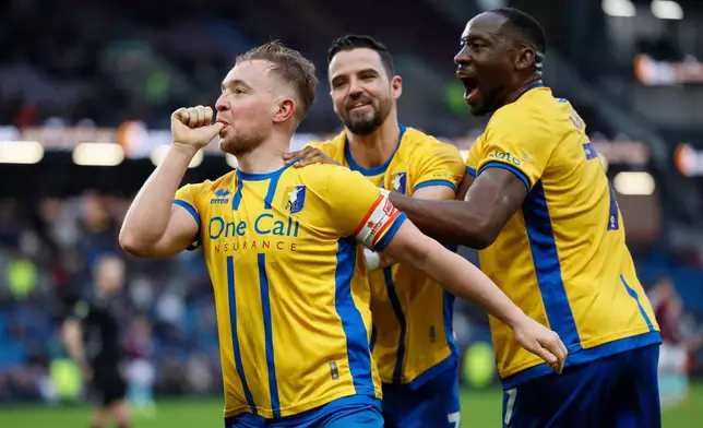 Mansfield Town's Louis Reed, left, celebrates scoring during the English FA Cup fourth round soccer match between Burnley and Mansfield Town in Burnley, England, Saturday Feb. 14, 2026. (Richard Sellers/PA via AP)
