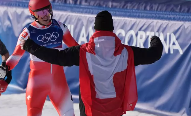 Switzerland's Franjo von Allmen, right, goes to hug his teammate Switzerland's Nef Tanguy at the finish area of an alpine ski men's slalom portion of a team combined race, at the 2026 Winter Olympics, in Bormio, Italy, Monday, Feb. 9, 2026. (AP Photo/Rebecca Blackwell)