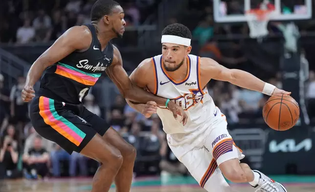Phoenix Suns guard Devin Booker (1) drives against San Antonio Spurs guard De'aaron Fox (4) during the first half of an NBA basketball game in Austin, Texas, Thursday, Feb. 19, 2026. (AP Photo/Eric Gay)